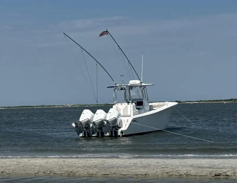 Slide: The Image of 2023 Front Runner 33 Center Console boat anchored near shore with triple engines. - 1