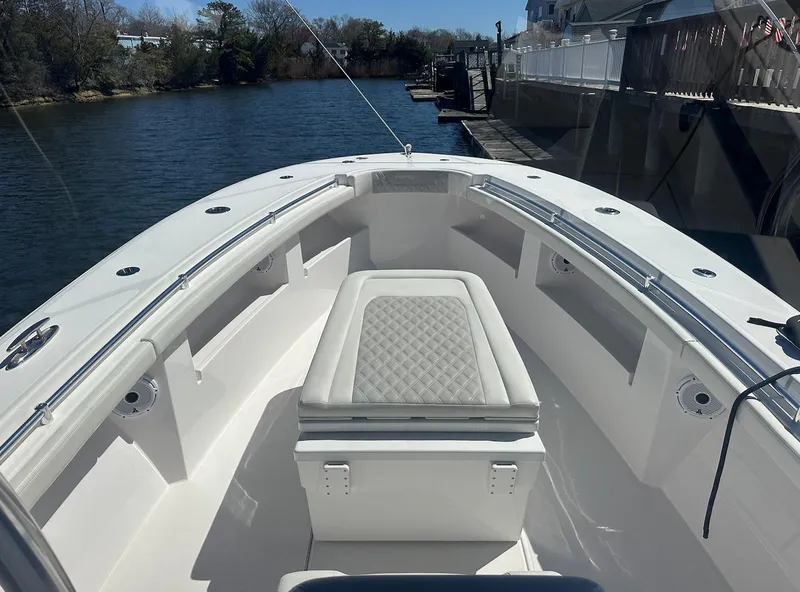 Slide: The Image of 2023 Front Runner 33 Center Console boat on a calm river, featuring sleek seating and storage. - 19