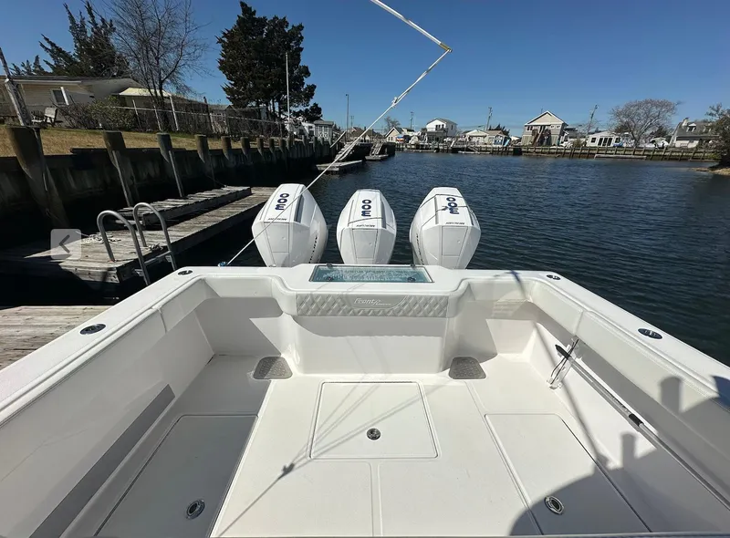 Slide: The Image of 2023 Front Runner 33 Center Console boat with triple outboard engines docked by a canal. - 8