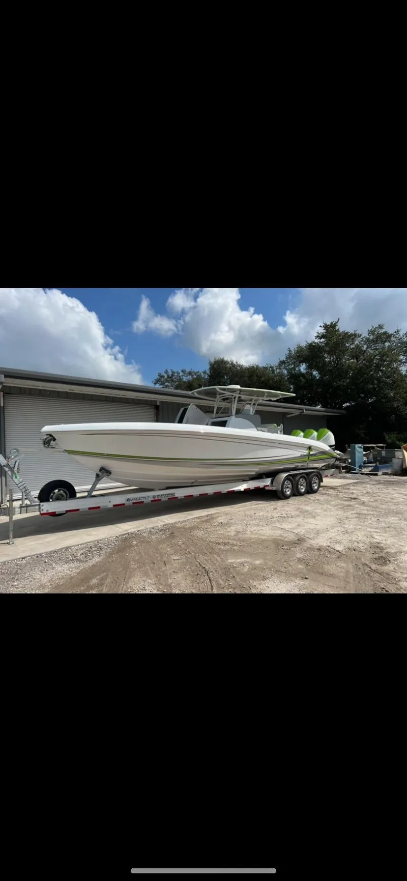 Slide: The Image of 2023 Statement 350 Open boat on trailer, parked outdoors under a partly cloudy sky. - 30