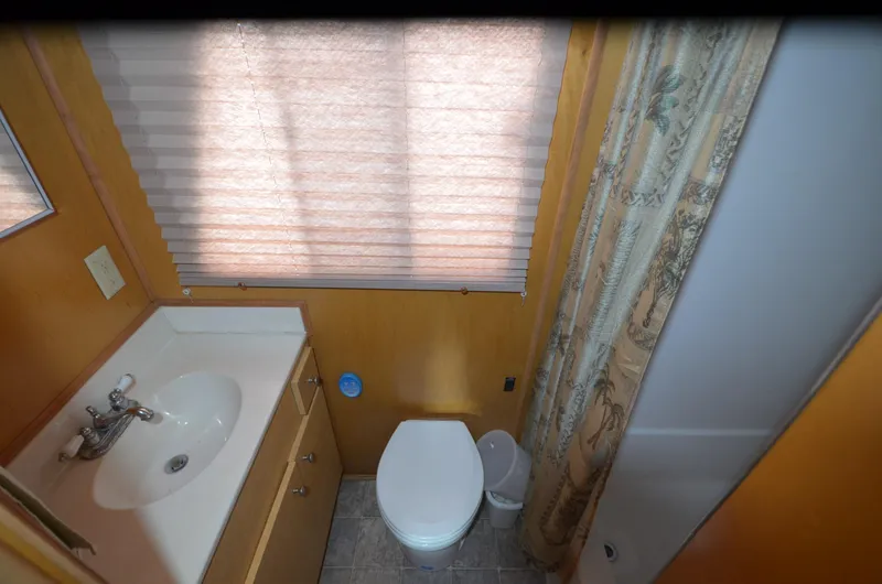 Slide: The Image of Compact bathroom in a 2008 Gibson 47 Classic, featuring sink, toilet, and shower with curtain. - 13
