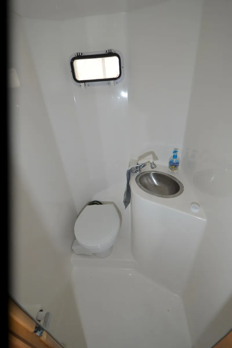Slide: The Image of Compact bathroom in a 2008 Gibson 47 Classic boat with toilet, sink, and porthole. - 22