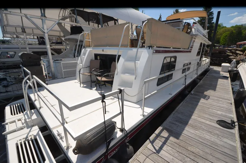 Slide: The Image of 2008 Gibson 47 Classic houseboat docked, featuring spacious deck and outdoor seating. - 24