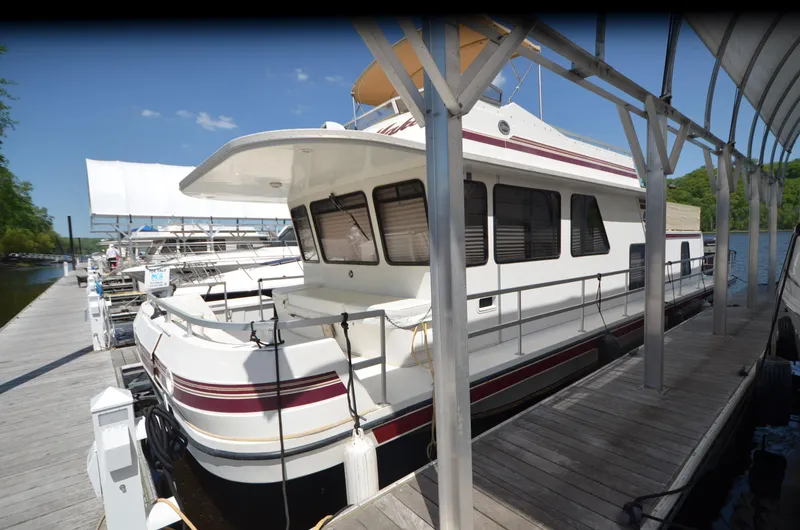 Slide: The Image of 2008 Gibson 47 Classic houseboat docked at a marina under a clear blue sky. - 26
