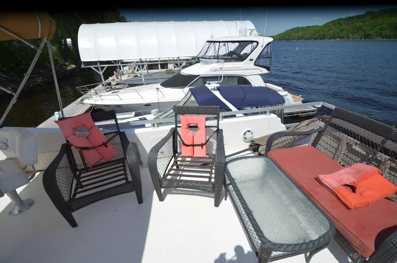Slide: The Image of 2008 Gibson 47 Classic yacht with deck seating, glass table, and scenic waterfront view. - 33