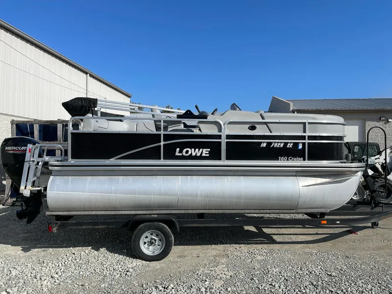 Slide: The Image of 2020 Lowe Ultra 160 Cruise pontoon boat on trailer, parked outdoors. - 2