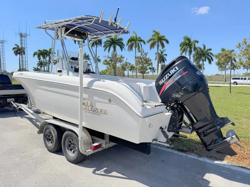 Slide: The Image of 2005 Sea Chaser 2100 Offshore boat with Suzuki outboard motor on trailer, palm trees in background. - 2