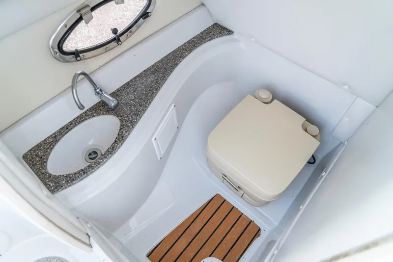 Slide: The Image of 2012 Crownline Eclipse E2 boat bathroom with sink, portable toilet, and wooden floor mat. - 23