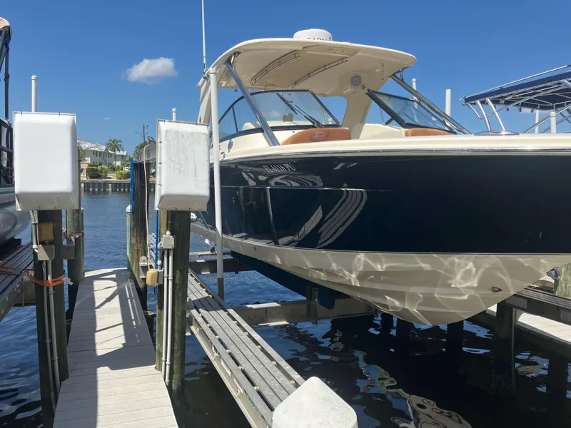 Slide: The Image of 2015 Scout 275 Dorado boat docked on a lift under clear blue skies. - 1