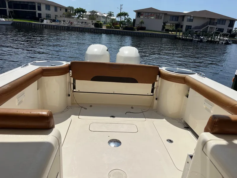 Slide: The Image of 2015 Scout 275 Dorado boat interior with tan seating, docked by waterfront homes. - 15