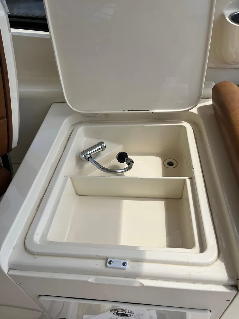 Slide: The Image of 2015 Scout 275 Dorado boat sink with faucet, open lid, and storage compartment. - 18
