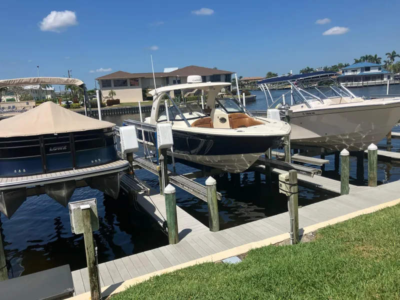 Slide: The Image of 2015 Scout 275 Dorado boat docked at a marina under clear blue skies. - 2