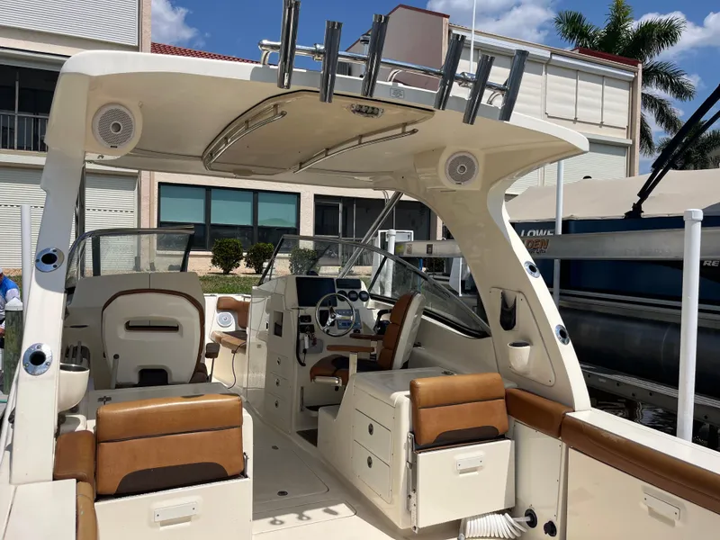 Slide: The Image of 2015 Scout 275 Dorado boat interior with seating and steering wheel, docked under sunny skies. - 9