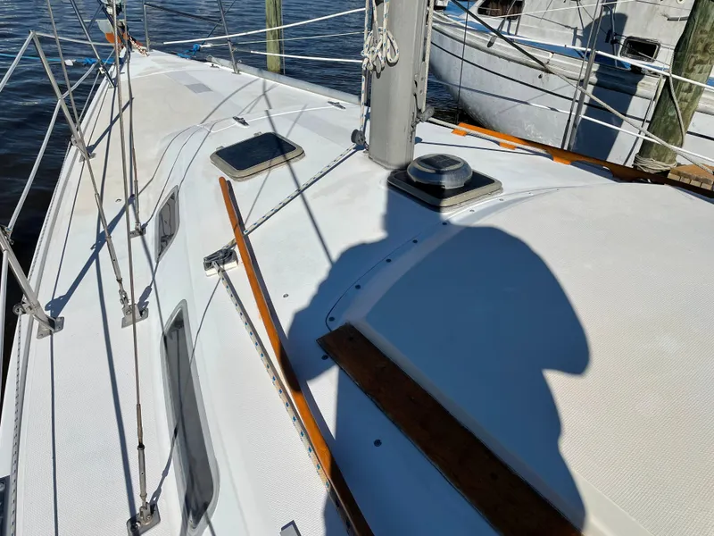 Slide: The Image of 1982 Catalina 30 sailboat deck with shadow, docked by the water. - 10