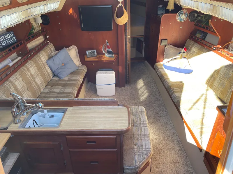 Slide: The Image of Interior of a 1982 Catalina 30 sailboat with cozy seating and compact kitchen area. - 23