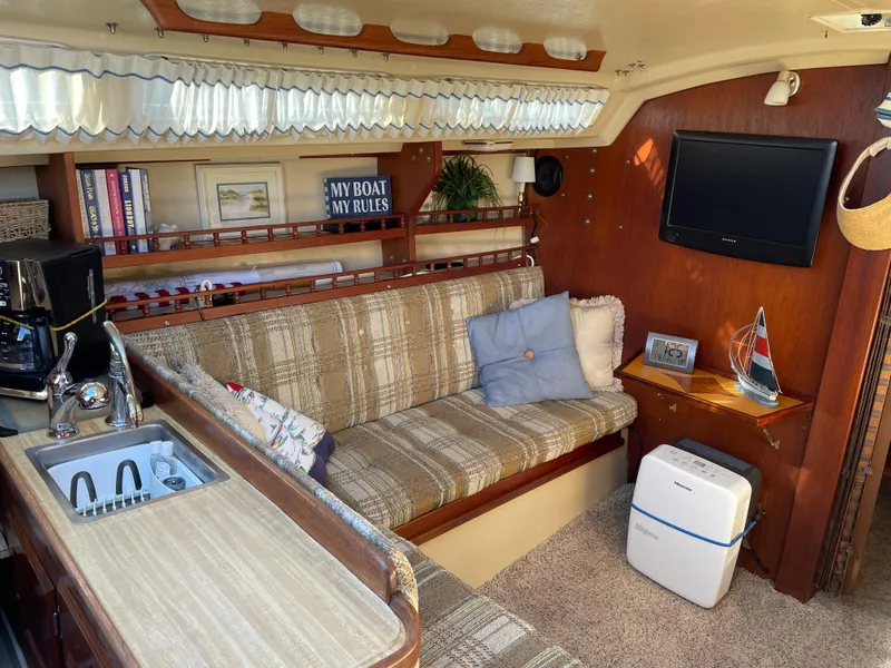 Slide: The Image of Cozy interior of a 1982 Catalina 30 sailboat with seating, kitchenette, and decor. - 37