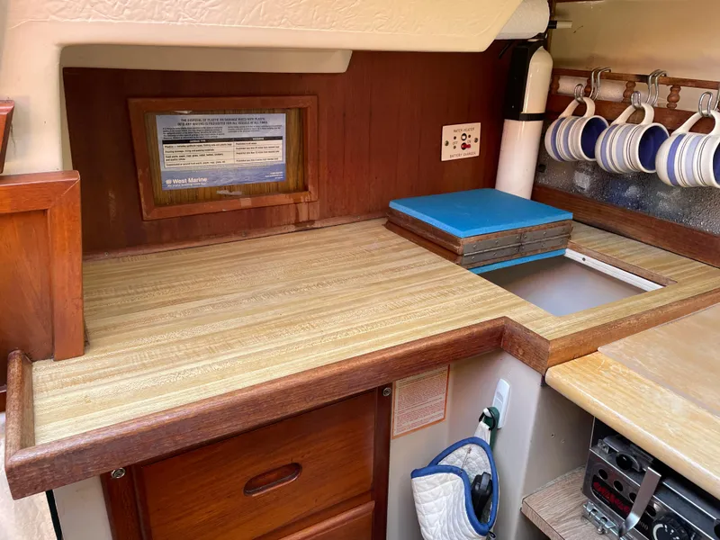 Slide: The Image of Interior of 1982 Catalina 30 sailboat with wooden cabinetry and countertop, featuring hanging mugs. - 42