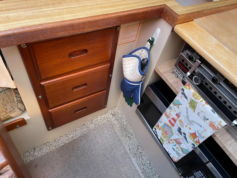 Slide: The Image of Interior of a 1982 Catalina 30 sailboat with wooden cabinets and nautical-themed decor. - 43