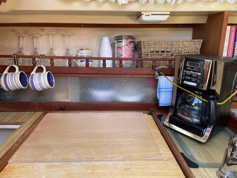 Slide: The Image of Galley of 1982 Catalina 30 sailboat with coffee maker and hanging mugs. - 44