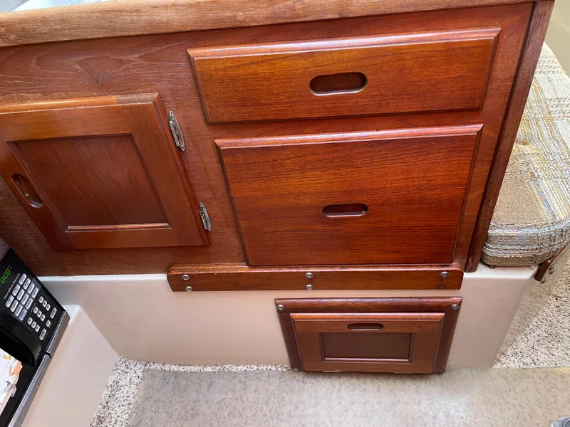 Slide: The Image of Wooden cabinetry inside a 1982 Catalina 30 sailboat, featuring drawers and a small door. - 49