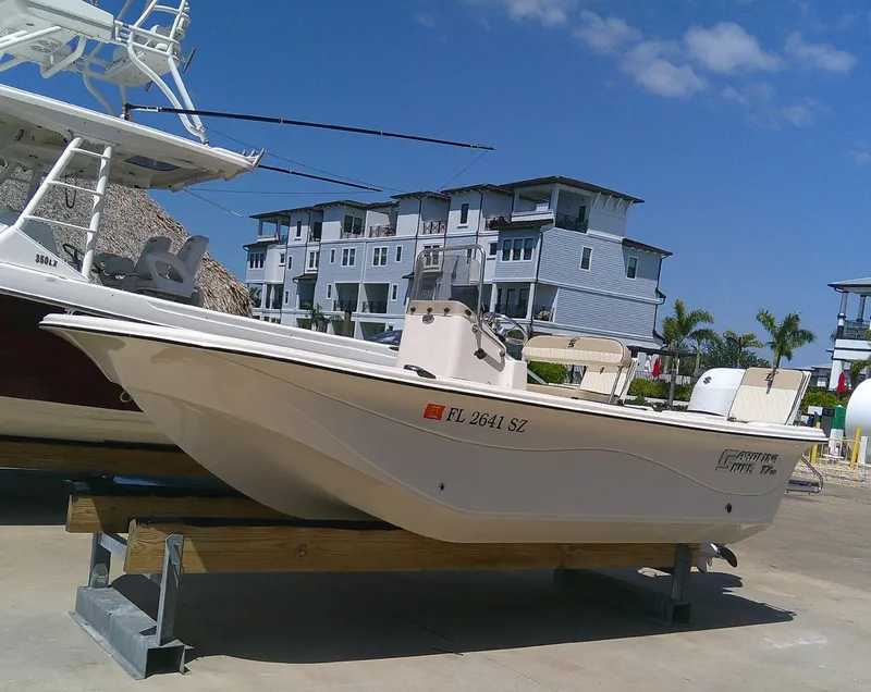 Slide: The Image of 2021 Carolina Skiff 17 LS boat on display, docked near modern buildings under a clear blue sky. - 9