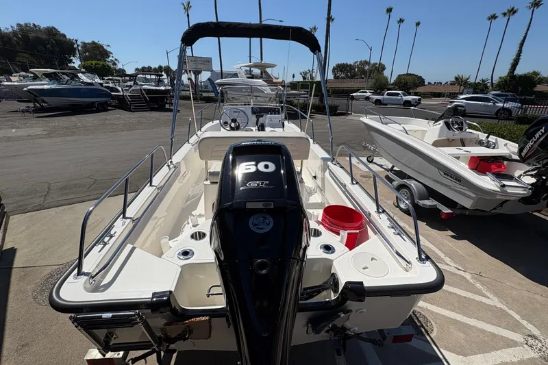 Slide: The Image of 2026 Boston Whaler 150 Montauk boat with 60 HP engine, parked at a marina. - 3