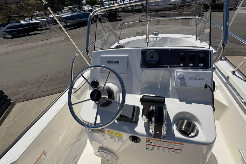 Slide: The Image of 2026 Boston Whaler 150 Montauk boat console with steering wheel and controls. - 4