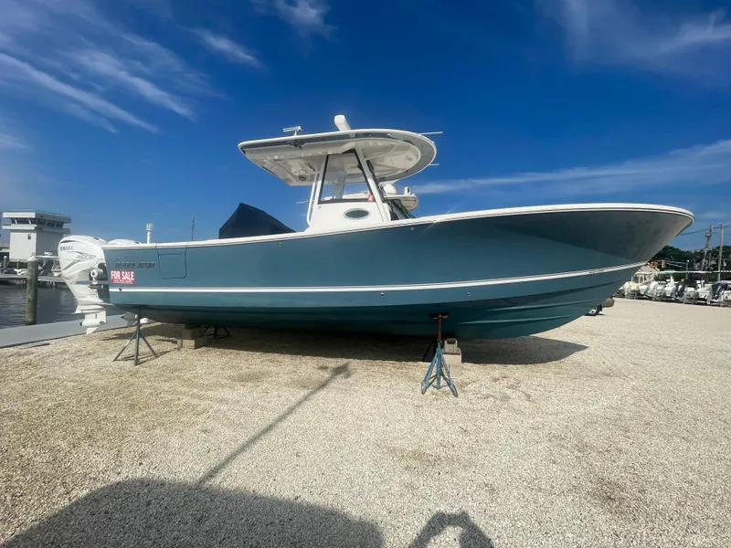 Slide: The Image of 2022 Regulator 31 boat for sale, displayed on a gravel lot under a clear blue sky. - 1