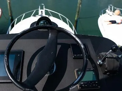 Slide: The Image of Steering wheel of a 1999 Viking Express boat with control panel, docked at marina. - 27