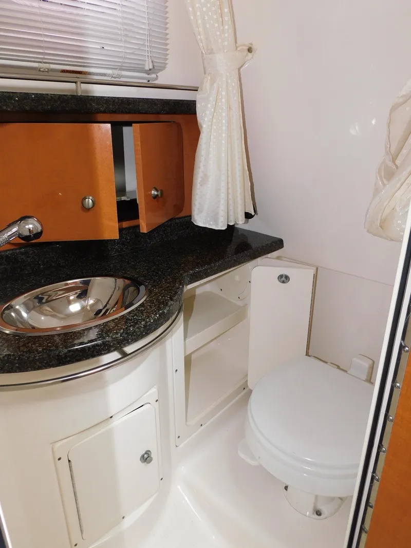 Slide: The Image of 2008 Robalo R305 Walkaround boat bathroom with sink, toilet, and storage cabinets. - 27