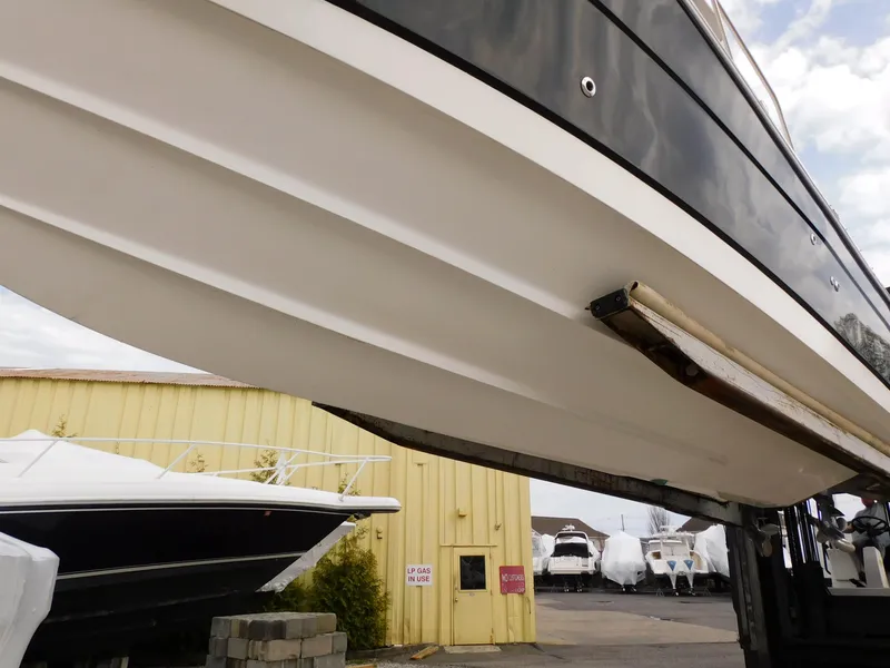Slide: The Image of 2008 Robalo R305 Walkaround boat hull in storage yard, yellow building background. - 4