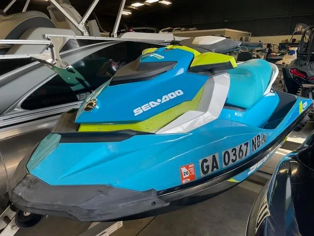 Slide: The Image of 2016 Sea-Doo GTI 130 SE jet ski in vibrant blue and green, parked indoors. - 1