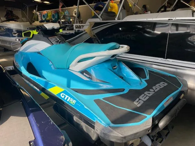 Slide: The Image of 2016 Sea-Doo GTI 130 SE jet ski in showroom, vibrant blue and teal design. - 3