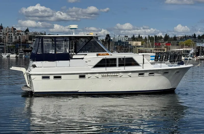 Slide: The Image of 1968 Hatteras 38 Double Cabin yacht on calm water, under a partly cloudy sky. - 1