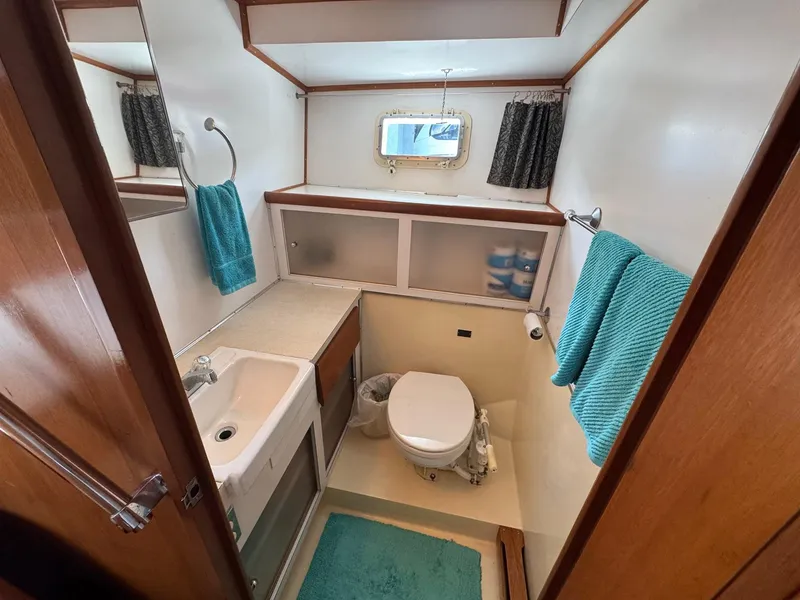 Slide: The Image of 1968 Hatteras 38 Double Cabin bathroom with sink, toilet, and teal towels. - 13