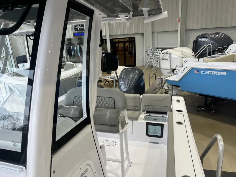 Slide: The Image of 2025 Sportsman Heritage 231 Center Console boat displayed in showroom with modern seating and engines. - 11
