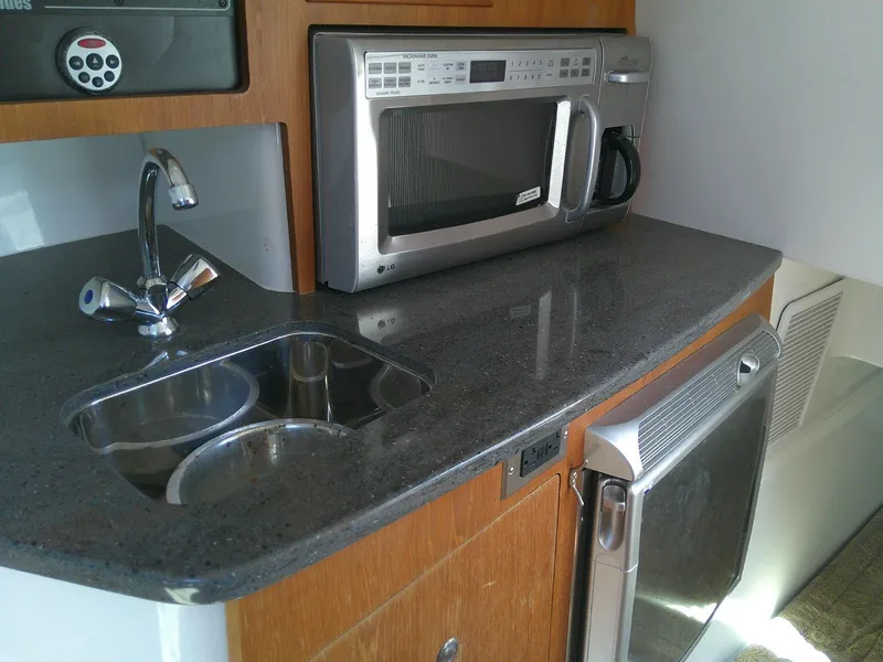 Slide: The Image of Compact kitchen area in a 2009 Everglades 350LX boat with sink, microwave, and countertop. - 20