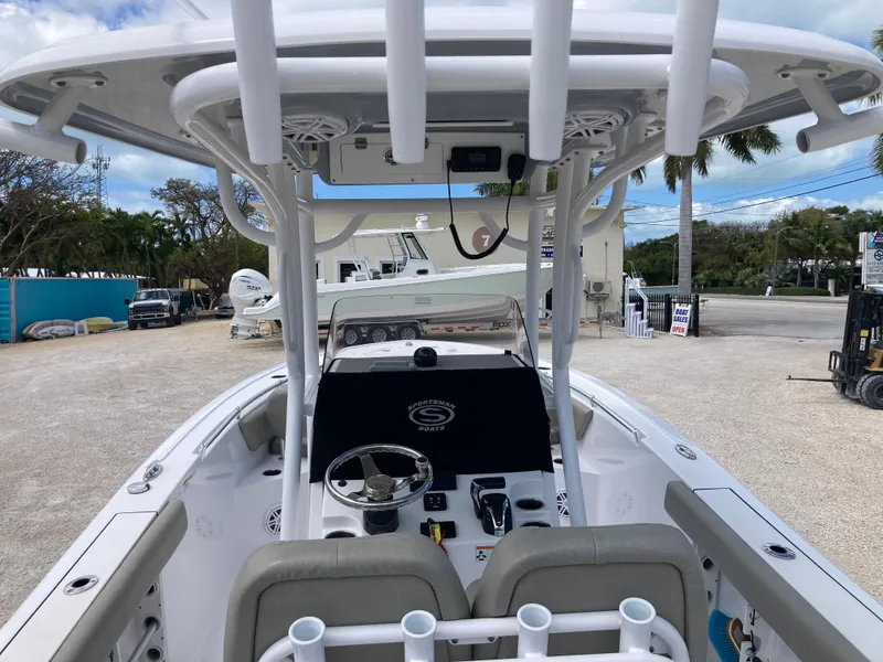 Slide: The Image of 2022 Sportsman 241 Heritage boat interior with helm, seating, and T-top in a marina setting. - 7