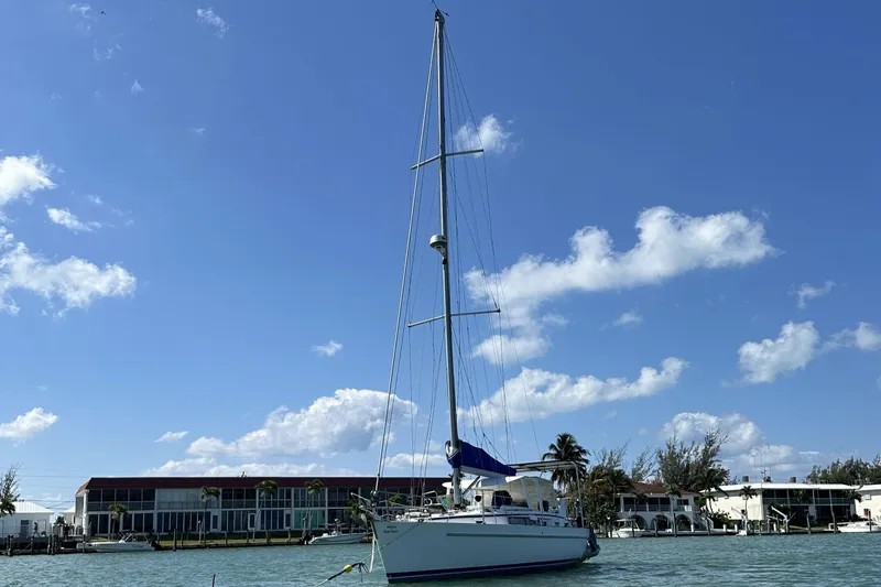 Slide: The Image of 1999 Beneteau Oceanis 40CC sailboat anchored near waterfront buildings under a clear blue sky. - 1