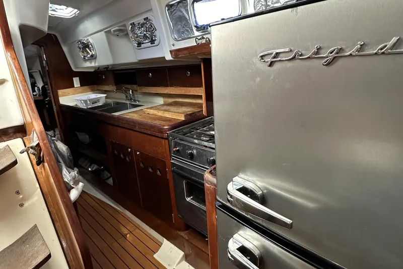 Slide: The Image of Interior of 1999 Beneteau Oceanis 40CC yacht kitchen with wooden cabinetry and stainless steel appliances. - 10