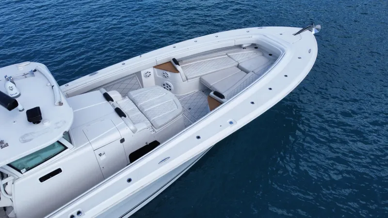 Slide: The Image of 2018 HCB 53 Sueños boat on calm blue water, showcasing sleek design and spacious deck. - 13