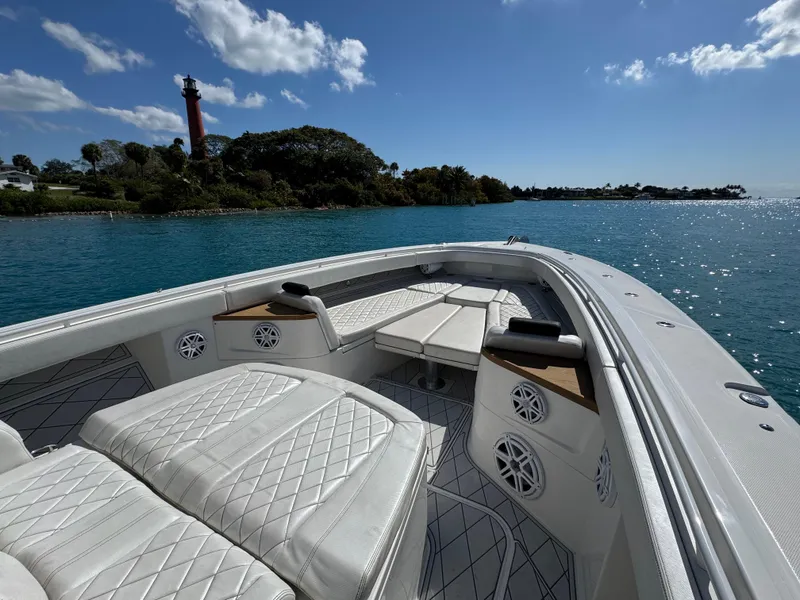 Slide: The Image of Luxurious 2018 HCB 53 Sueños boat with white seating, cruising near a scenic coastline. - 18