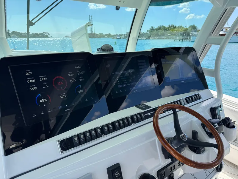 Slide: The Image of 2018 HCB 53 Sueños helm with advanced navigation displays and wooden steering wheel, overlooking blue waters. - 19