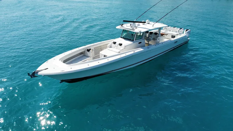 Slide: The Image of 2018 HCB 53 Sueños boat on clear blue water, showcasing sleek design and spacious deck. - 2