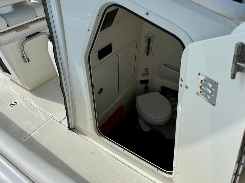 Slide: The Image of 2015 Boston Whaler 250 Outrage boat interior with open door revealing compact restroom. - 30