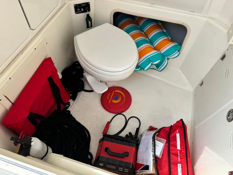 Slide: The Image of 2015 Boston Whaler 250 Outrage interior with toilet, safety equipment, and colorful cushions. - 31