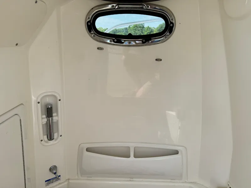 Slide: The Image of Interior of a 2015 Boston Whaler 250 Outrage boat, featuring a small window and storage area. - 32