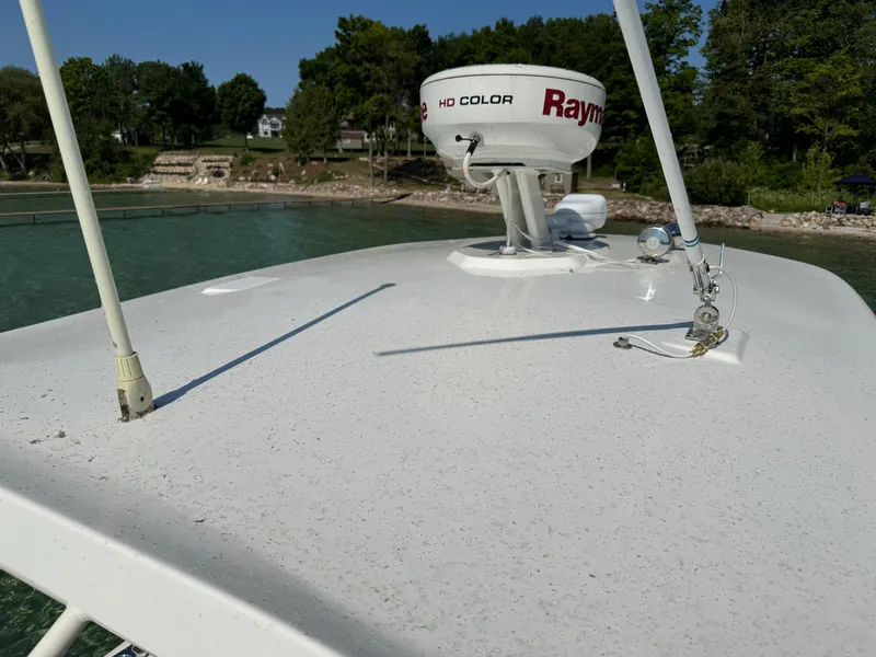 Slide: The Image of 2015 Boston Whaler 250 Outrage boat with radar equipment, docked near a scenic shoreline. - 34