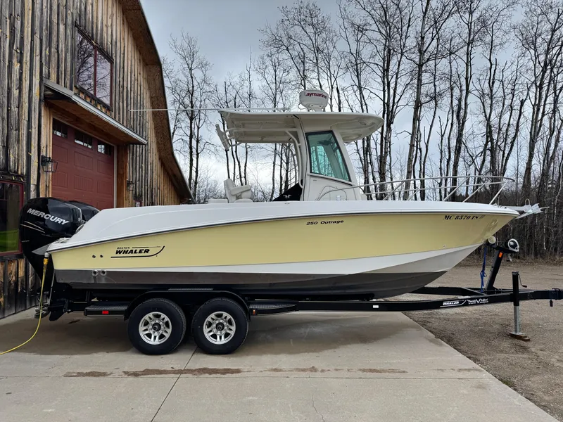 Slide: The Image of 2015 Boston Whaler 250 Outrage boat on trailer beside rustic building. - 4