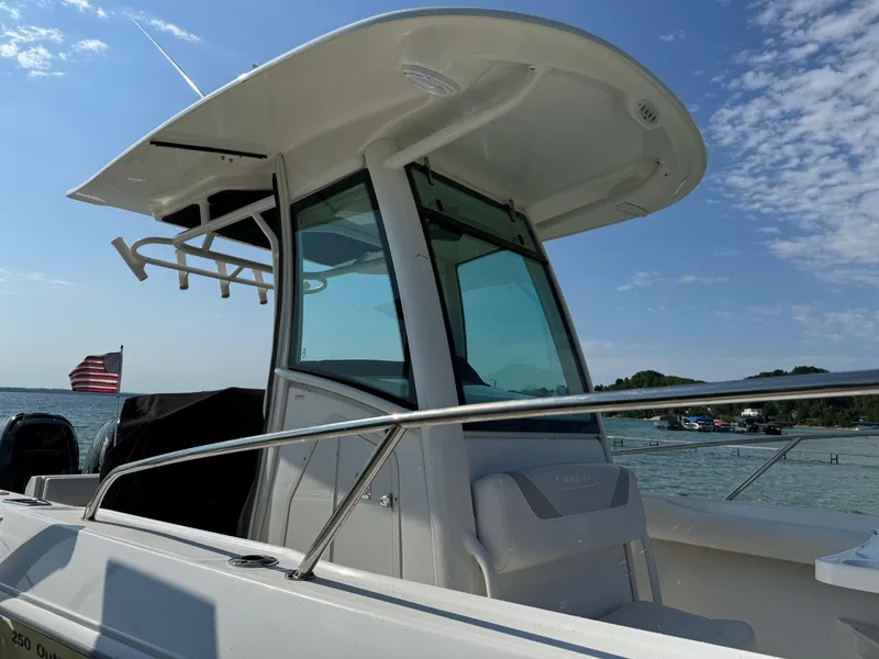 Slide: The Image of 2015 Boston Whaler 250 Outrage boat on water, clear sky, American flag visible. - 7